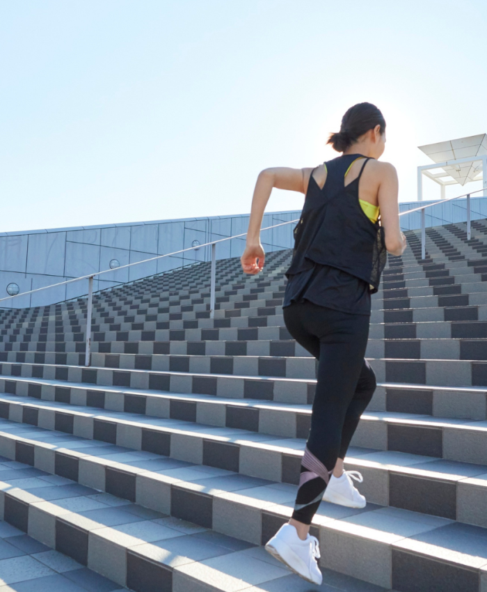 Mulher com roupas esportivas subindo uma grande escadaria, exemplificando o poder da constância