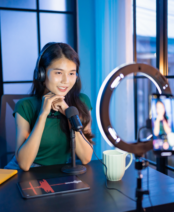 Mulher Asiática em frente à câmera do celular com ring light ligado para criar conteúdo