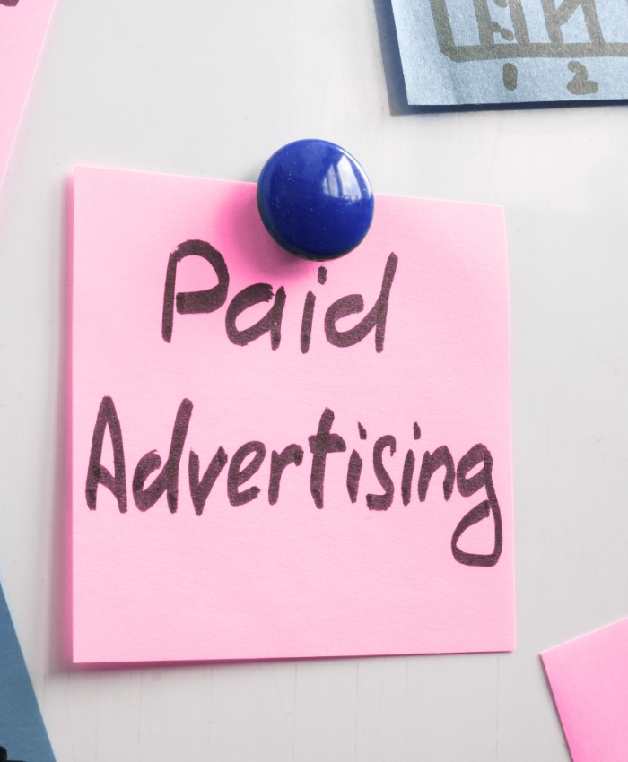 Post-its presos a um mural com taxas coloridas com a frase paid advertisin - sugerido a ideia de tráfego pago