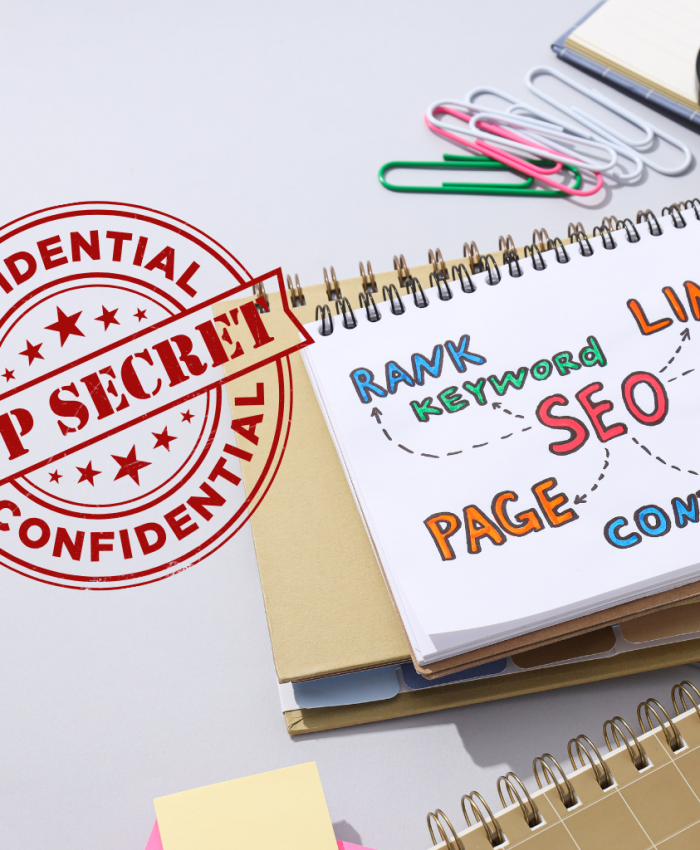 Caderno sobre uma mesa onde está escrito SEO, link, page. Contém uma lupa e o carimbo top secret